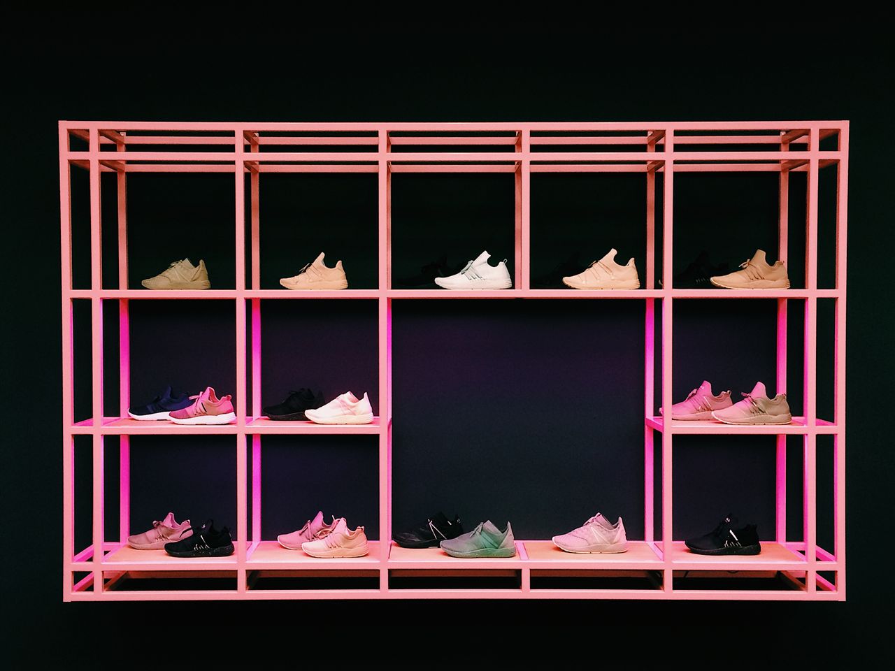 Colorful sneakers arranged on a pink shelf, showcasing modern design and fashion.